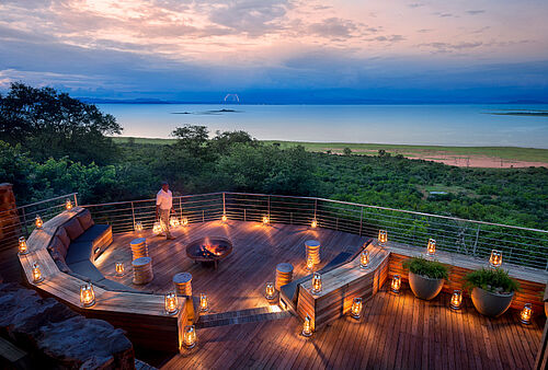 Beleuchteter Feuerstelle auf dem Balkon der Unterkunft Bumi Hills mit Blick über einen Wald auf den Lake Kariba
