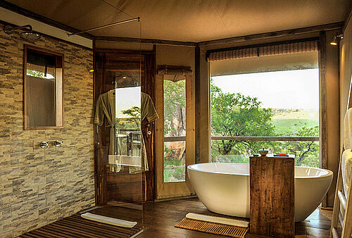 Luxuriöses Badezimmer mit Badewanne und Blick auf den Busch in der Kuria Hills Lodge in der Serengeti