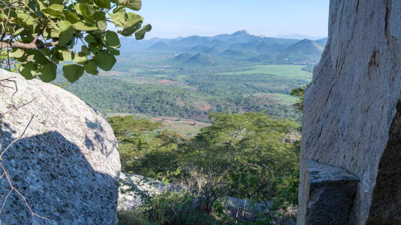 Atemberaubender Blick durch Granitfelsen auf eine grüne afrikanische Landschaft mit Hügeln im Hintergrund