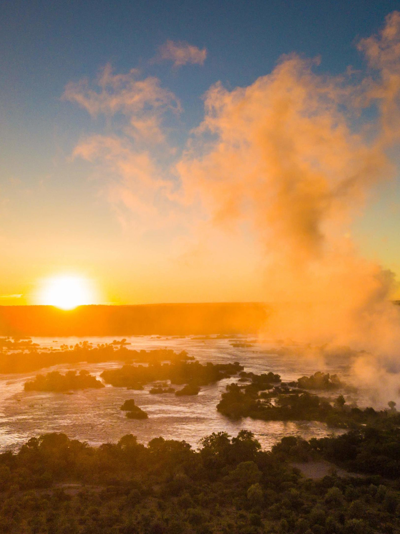 Das tosende Wasser der Victoriafälle trifft auf die Ruhe des Sonnenuntergangs